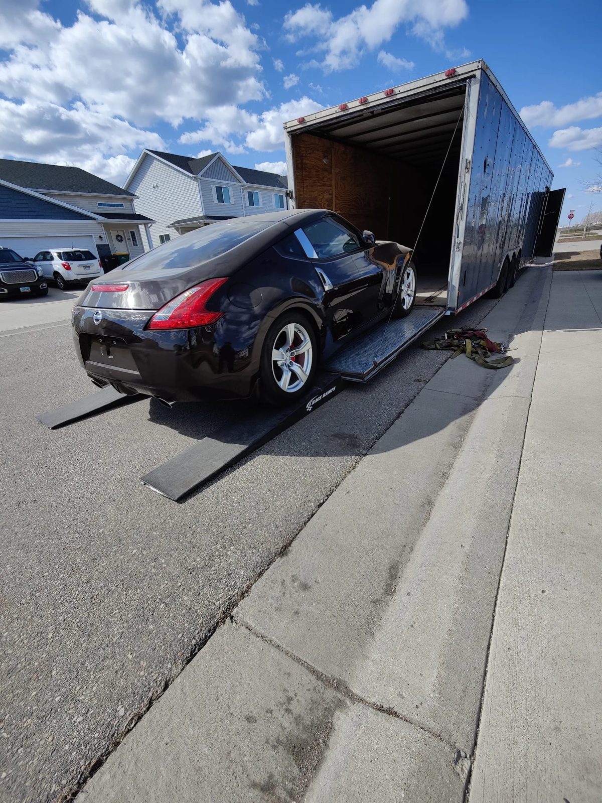 A car driving up the ramps into an enclosed trailer